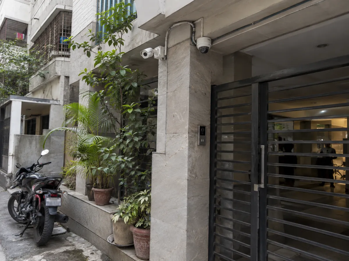 CCTV dome and bullet cameras with a video intercom at an apartment building gate in Dhaka